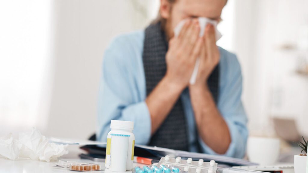 Amidst medication, a person battles flu symptoms, an image representing the flu treatment in chicago urgent care's commitment to providing relief during flu season.