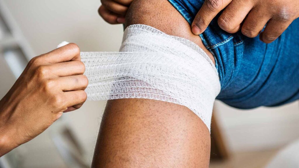 A medical professional carefully bandages a knee, a common practice at injuries treatment in illinois urgent care to support recovery from physical injuries.