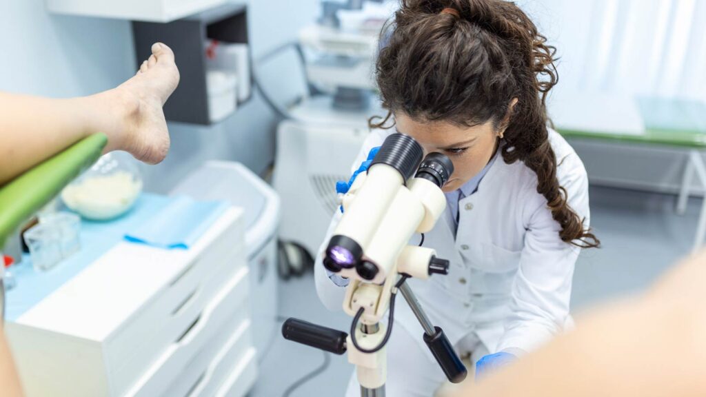 Focused on her microscope, a medical professional conducts a detailed analysis, possibly part of an abnormal pap smear service in Illinois urgent care clinic.