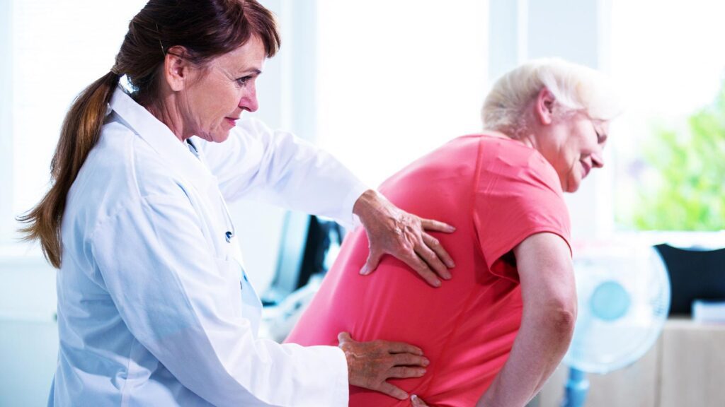 In aches pains treatment in illinois urgent care, a doctor assists a patient with back pain, exemplifying dedicated care in Illinois' medical facilities.