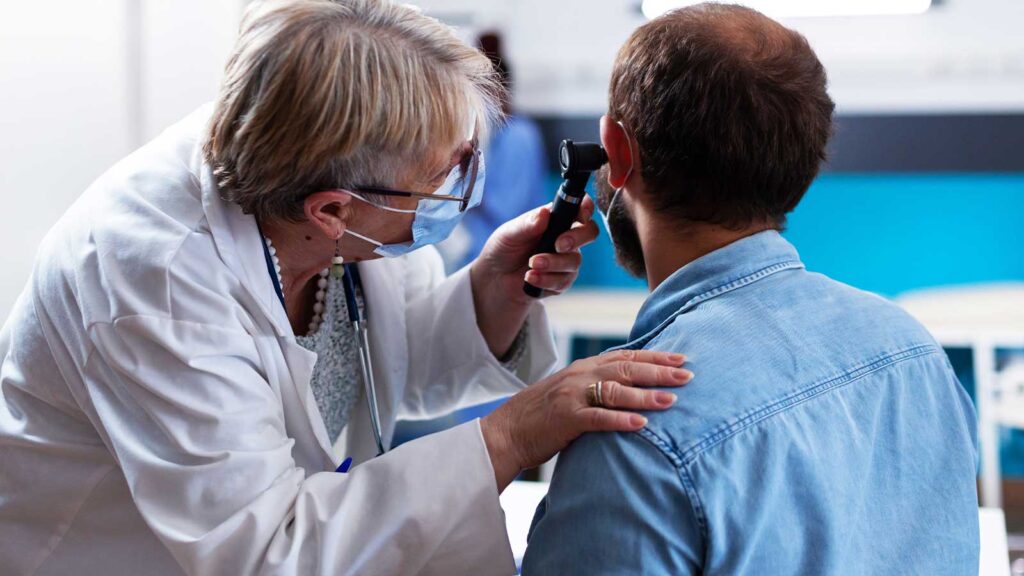 A physician inspects a patient's ear, indicative of the meticulous ear infection treatment in Chicago urgent care facilities.