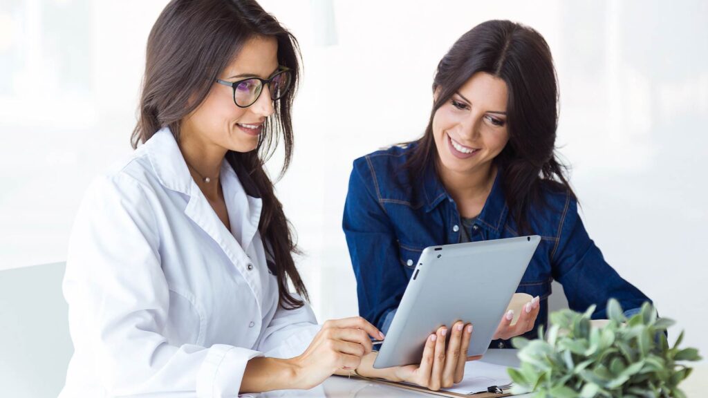 Two professionals engage over a tablet, likely discussing medication details for a refill prescription service in Chicago urgent care setting, emphasizing patient-physician collaboration.