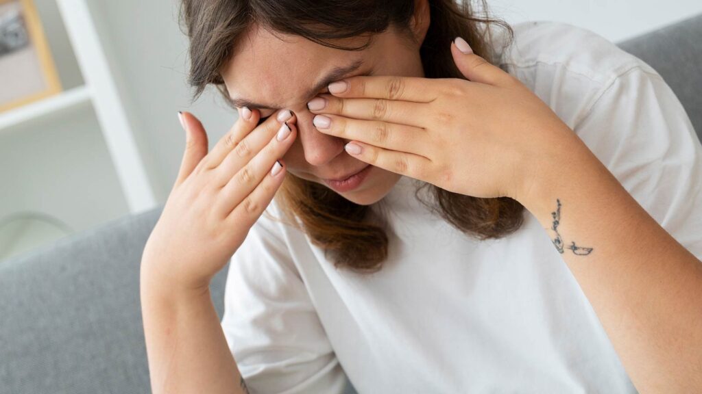A distressed individual covers their eyes, symptomatic of the discomfort managed at sinus treatment in Chicago urgent care.