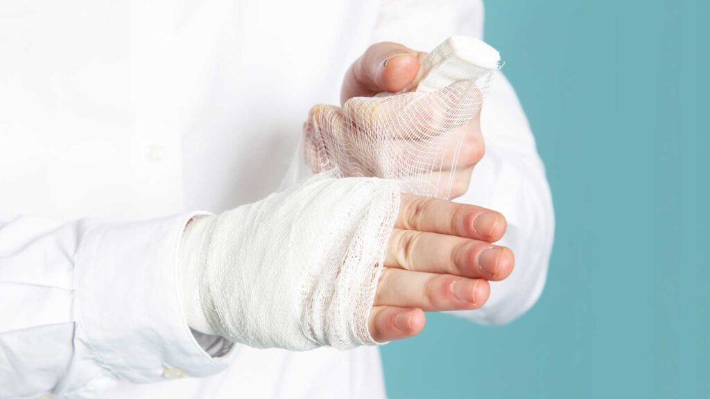 The image showcases a hand wrapped in a fresh white bandage, indicating professional wound cleaning treatment in Illinois urgent care facility.
