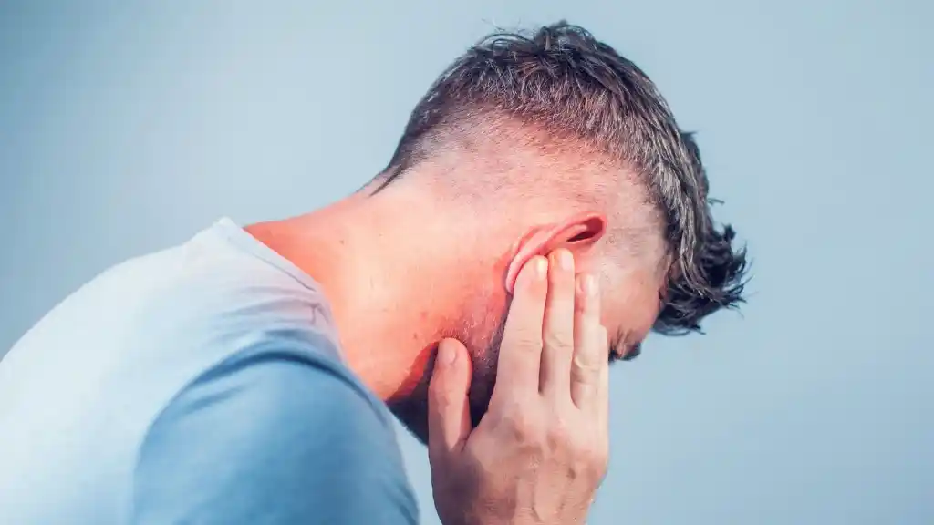 man holding her ear and jaw in pain due to ear infection